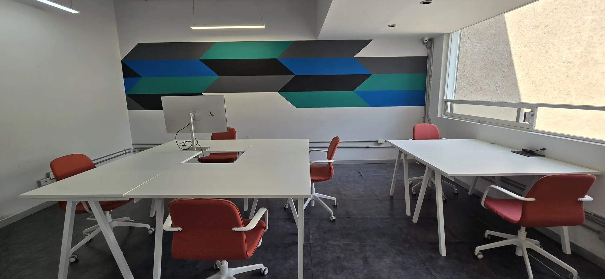The open Interamerica Studios coworking floor, with shared worktables and a blue geometric wall.